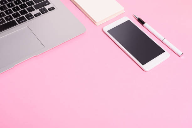 istock Business concept: office desktop with laptop, mobile phone. Pink background. 960520404
