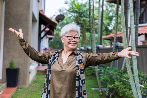 radosna aktywna seniorka witająca widza w jej ogrodzie. - arms outstretched greeting house women zdjęcia i obrazy z banku zdjęć