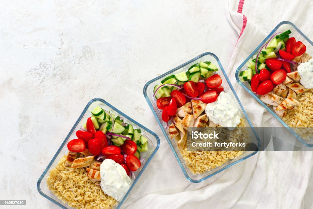 Greek chicken with tzatziki prepared and ready to eat in a take away  lunch boxes Greek style grilled chicken breasts with tzatziki and freshly diced vegetables prepared and ready to eat in a take away lunch boxes, view from above, space for a text Preparing Food Stock Photo