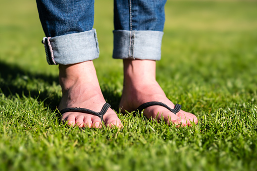 Flip Flops on a meadow on a girl with a jeans.