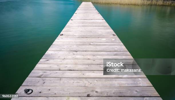 Wooden Pier Jutting Out Into A Turquoise And Blue Lake With Golden Reeds In The Background Stock Photo - Download Image Now