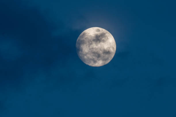 gorgeous full moon in a dark blue night sky gets covered by soft wispy dark clouds A gorgeous full moon in a dark blue night sky gets covered by soft wispy dark clouds apollo 11 stock pictures, royalty-free photos & images