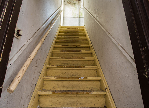 Old dirty damaged abandoned wooden stairs to the garret. Entrance to the attic. in the dark
