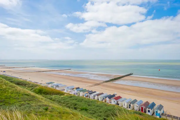 Photo of Beach cabins along hilly dunes on a recreational beach in sunlight in spring