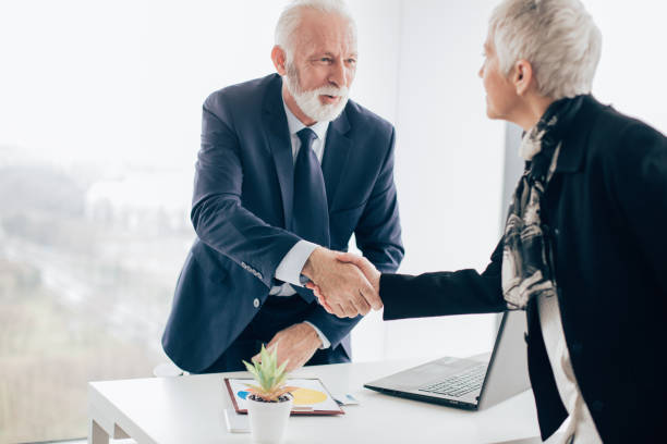 istock Senior coworkers shaking hands in office 960567130