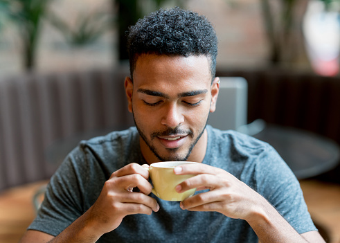 Hombre feliz bebiendo una taza de café en una cafetería photo