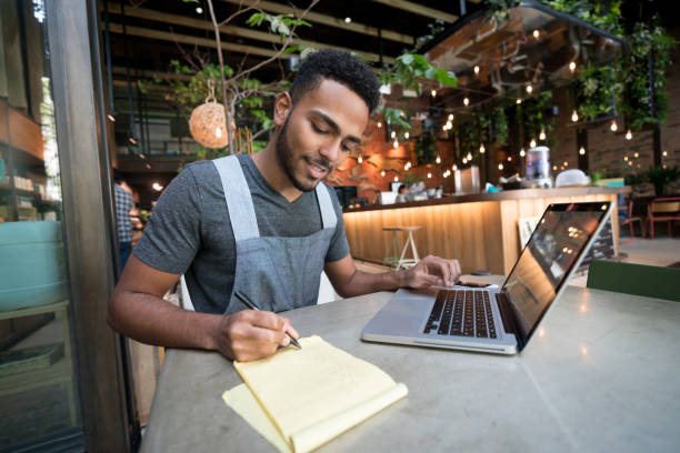 homem feliz, fazendo os livros em um restaurante - owner small business restaurant african ethnicity - fotografias e filmes do acervo