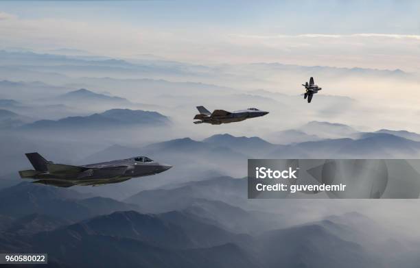 Fighter Jets Flying Over The Misty Mountains At Dusk Stock Photo - Download Image Now