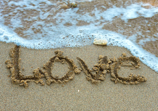 istock Write the word love on the beach. Soft focus wave. 960583476