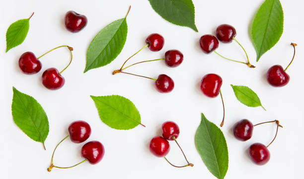 Cherry background Cherry background. Composition of red cherry berries and green leaves on white background, close up. Beautiful Food Wallpaper or Web banner. Top view. Flat lay. cherry stock pictures, royalty-free photos & images