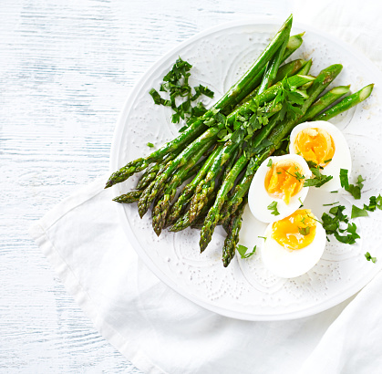 Roasted Green Asparagus with Boiled Eggs and Fresh Parsley; flat lay