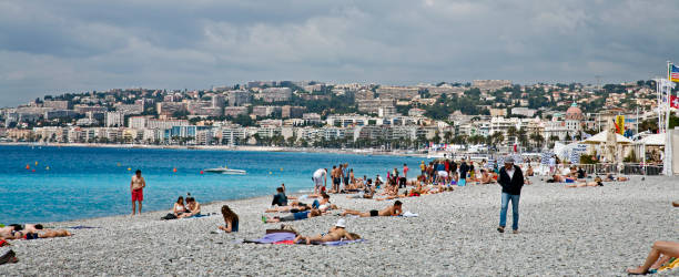 sun bathers on the french shore of nice - swisse imagens e fotografias de stock