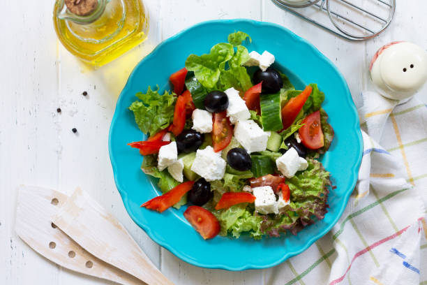 griechischer salat mit frischem gemüse, schafskäse und schwarzen oliven in einer blauen platte auf weißer holztisch. oben flach legen hintergrund anzeigen. - 11270 stock-fotos und bilder