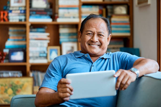 istock Smiling senior man with tablet pc on sofa at home 960594844