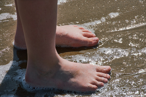 Girls' feet in the surf of the North Sea in Egmond aan Zee