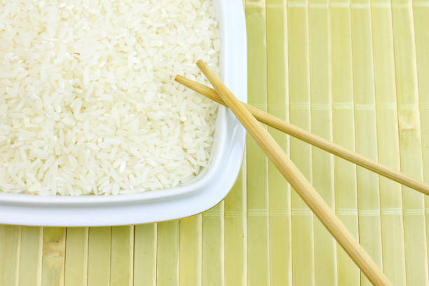 istock A bowl of raw white rice with chopsticks on bamboo background 960604926