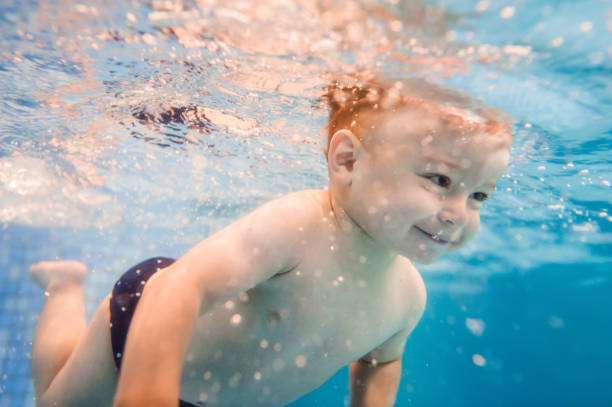 lilla bebis, pojke simma under vatten i plaskdamm. dykning baby. lärande spädbarn barn att simma. njuta av simning och bubblor. - baby swim under water bildbanksfoton och bilder