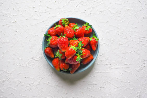 Ripe strawberries in a bowl on a white table.