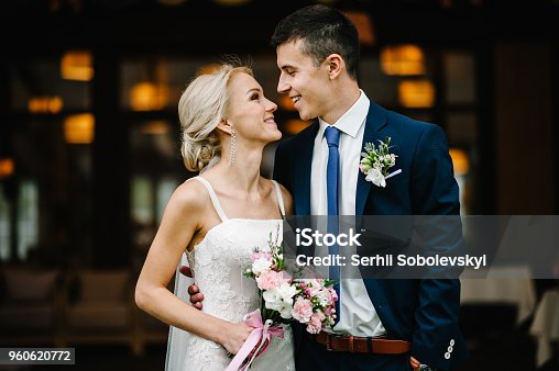istock Romantic couple newlyweds, bride and groom holding bouquet of pink and purple flowers and greens with ribbon at the wedding ceremony. Happy and joyful wedding moment. 960620772