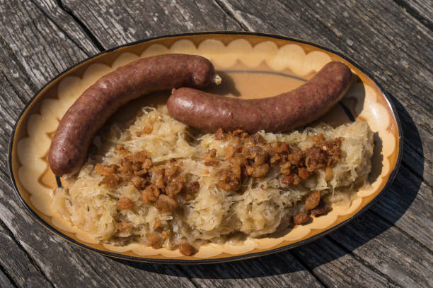 Portion of Carniolan sausage and Sauerkrautwith with greaves on wooden table outdoors.