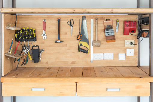 Wooden workbench at workshop. Lot of different tools for diy and repair works. Wood desk for product display. Copyspace. Labour day.