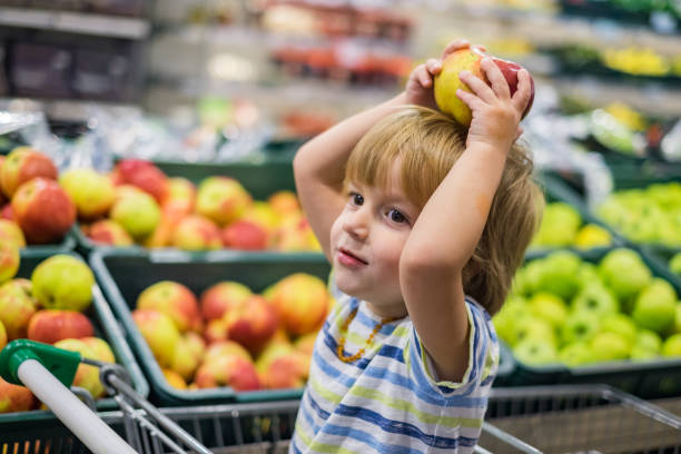 istock Small cute boy playing with apple in the store 960637820
