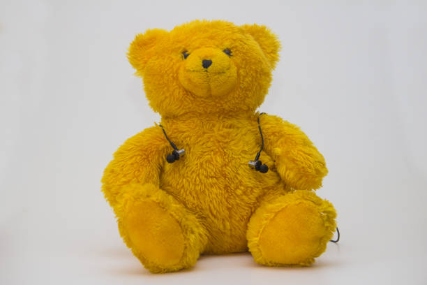 istock Yellow teddy bear with earphone against white background 960638238