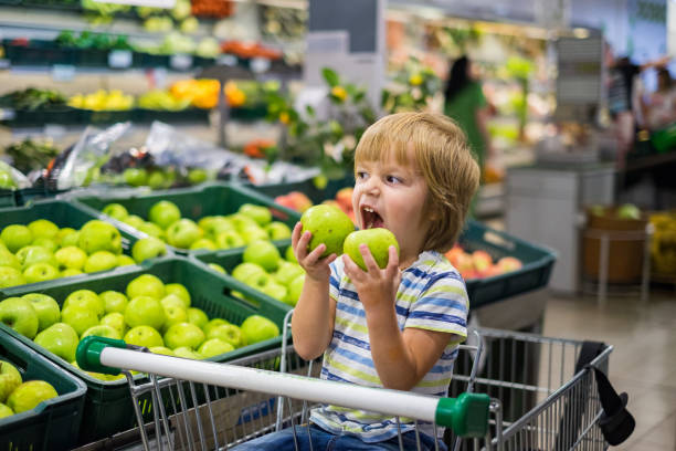 Cute boy biting two apple in the store