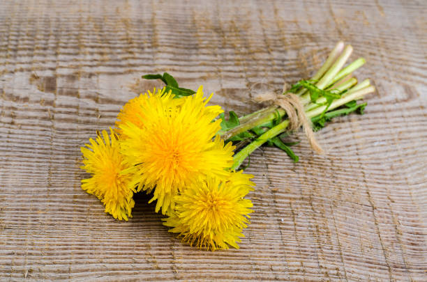 istock Yellow blossoming dandelions on wooden surface 960640658
