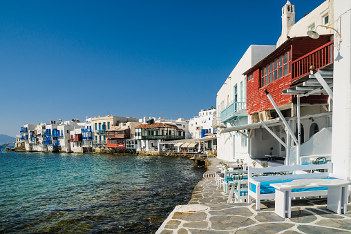 Mykonos, Greece-May 9, 2018-Small tables of cafes, bars and restaurants crowd the narrow sidewalk leading through the section of Mykonos town known as \
