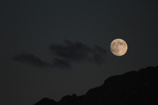 view of a mountain silhouette, cloud and full moon