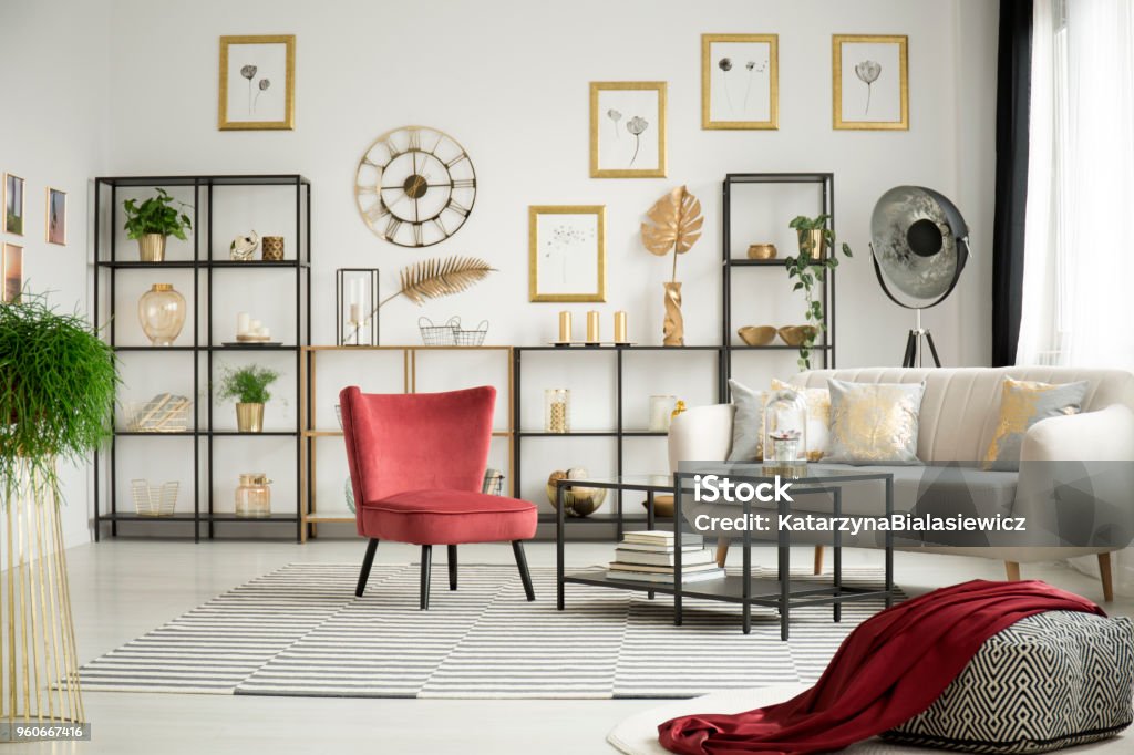 Armchair in white living room Pink, velvet armchair standing in the middle of a white living room interior with beige sofa, metal racks and plants Apartment Stock Photo