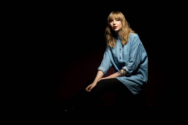 Confident woman sitting against black background