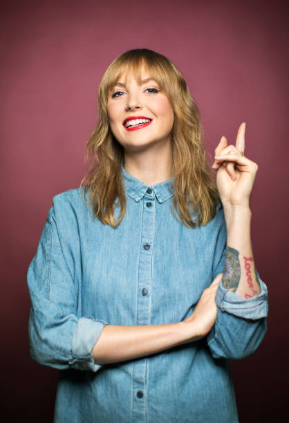 Smiling young woman pointing on pink background