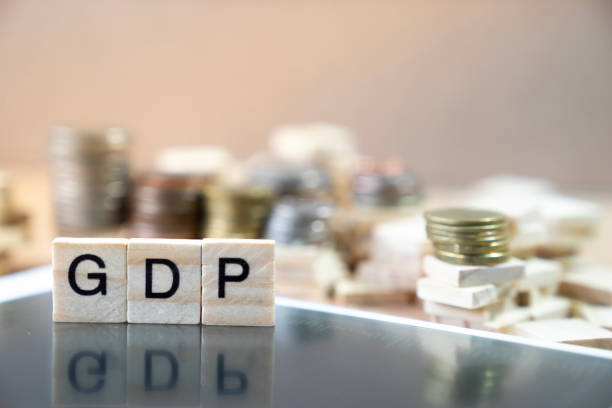 GDP  Word Written In Wooden Cube reflection on black mirrow with money stack as graph in background stock photo