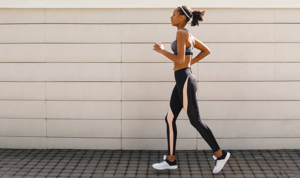 istock Young woman jogging near a wall, side view 960710494