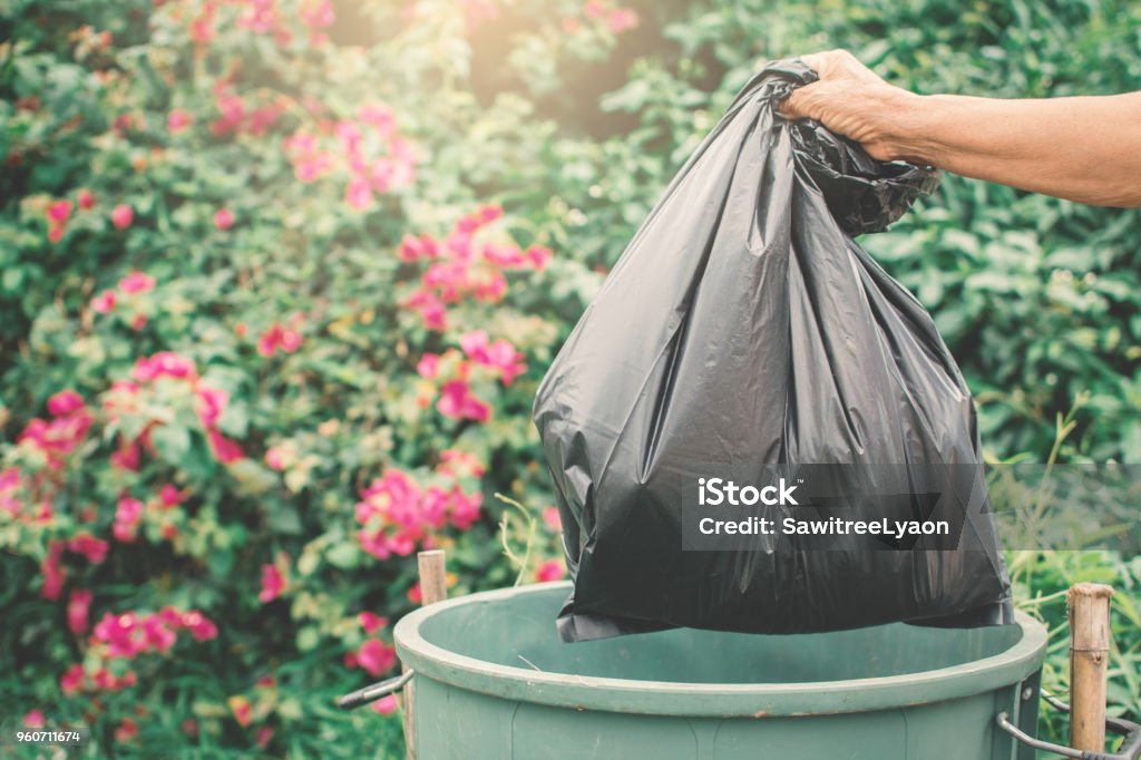 Old hand holding plastic bag in to trash Garbage Stock Photo
