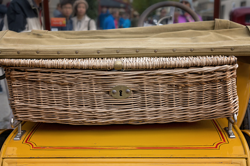 A wicker picnic basket on the boot of a vintage car