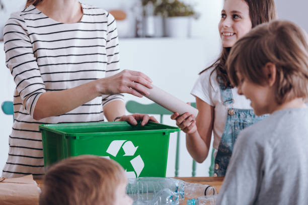 Mother teaching kids segregating waste Close-up of mother teaching kids how to segregating waste at home recycling bin photos stock pictures, royalty-free photos & images