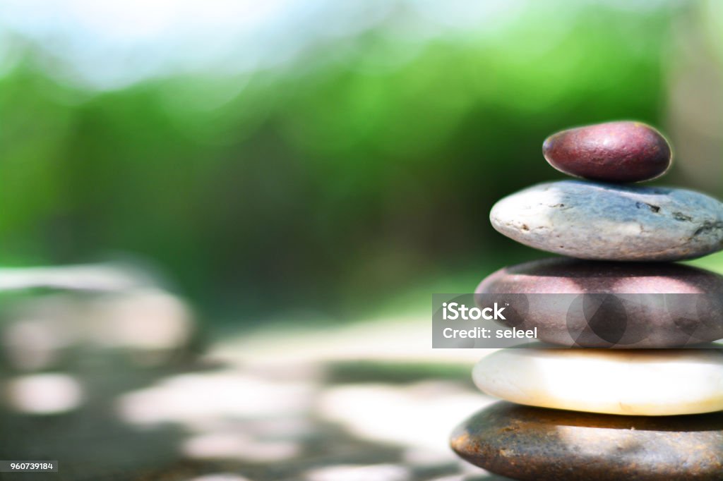 Zen stones on wooden floor with shadow and green natural background left space position. Wellbeing Stock Photo