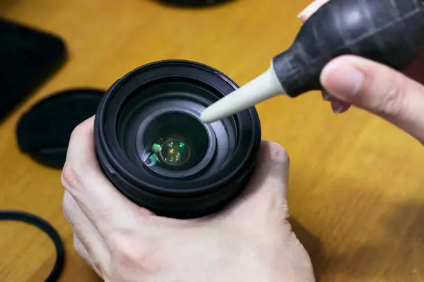 Cleaning dust on camera lens surface by using hand blower pumper