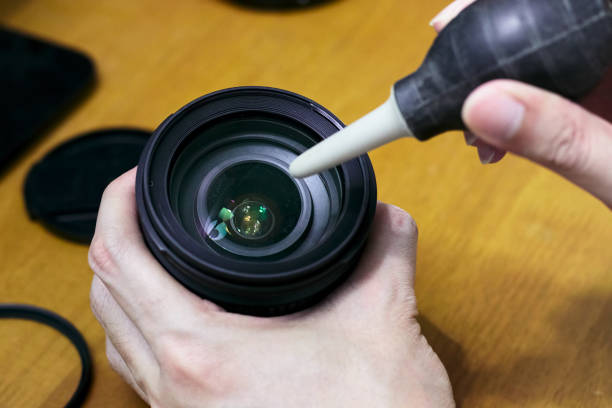 очистка пыли на поверхности объектива камеры с помощью ручной воздуходувки насос - pumper стоковые фото и изображения
