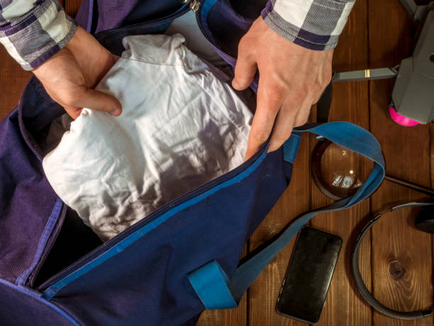 istock hand packing clothes in baggage  bag with travel accessories 960743226