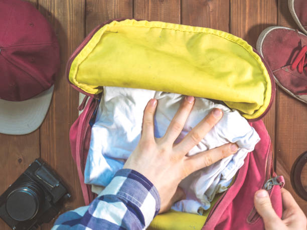 istock hand packing clothes in the backpack for travel with accessories concept 960743970