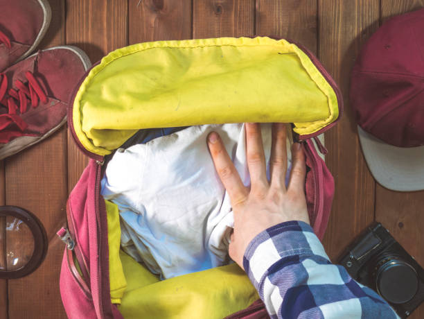istock hand packing clothes in the backpack for travel with accessories concept 960743978