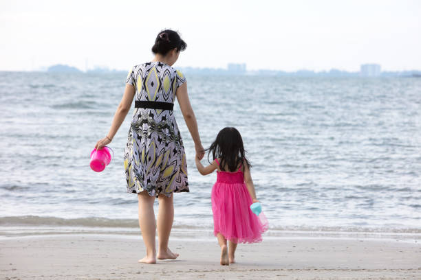 Asian Chinese mum and daughters playing sand together at beach outdoor