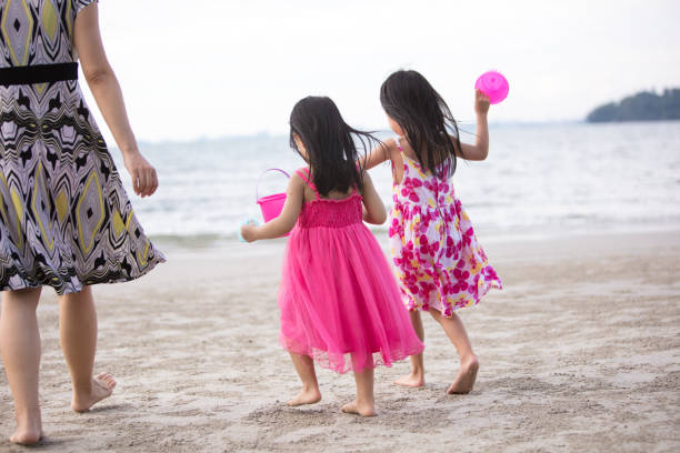 Asian Chinese mum and daughters playing sand together at beach outdoor