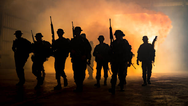 istock Silhouette People With Weapons Walking Against Smoke During Sunset 960777446