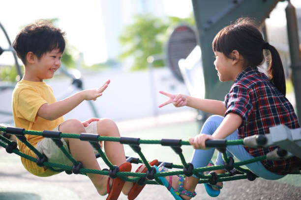 Cute little boy and girl playing a rock-paper-scissors game stock photo