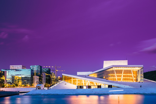 Oslo, Norway - July 31, 2014: Night Evening View Of Illuminated Norwegian National Opera And Ballet House Among Contemporary High-Rise Buildings. Toned Photo In Ultra Violet Color.